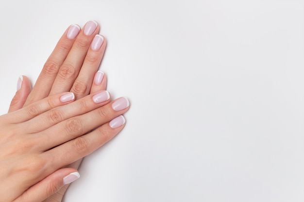 French manicure. Nude nails covered with gel polish on a white background