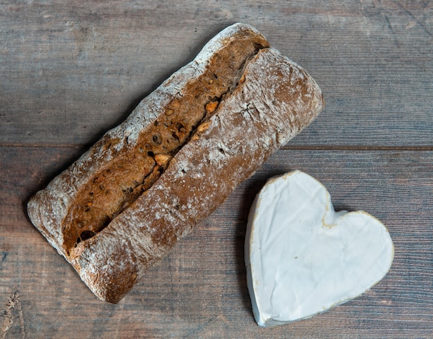 A French Neufchatel cheese shaped heart on wooden surface