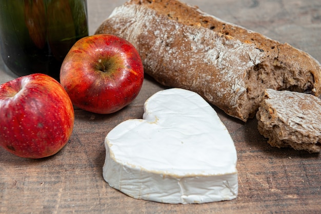 A French Neufchatel cheese shaped heart on wooden surface