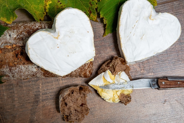 A French Neufchatel cheese shaped heart on wooden surface