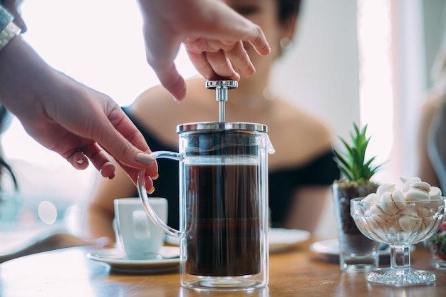 French press coffee. Friends waiting for coffee at the table in a Brazilian cafe shop.