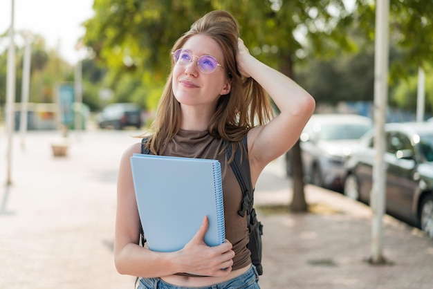 Photo french student french girl with glasses at outdoors having doubts and with confuse face expression