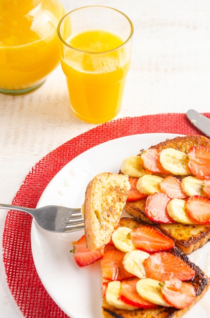 French toast with strawberries banana and honey Orange juice White background