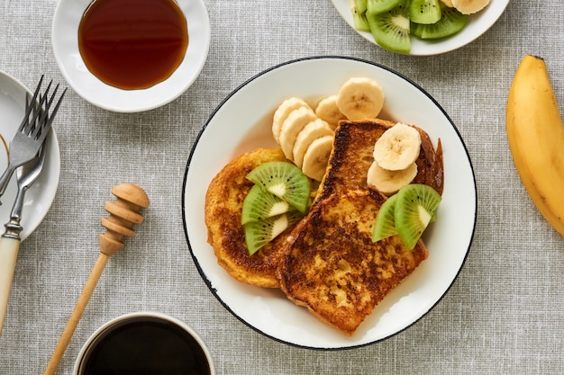 French toasts with kiwi and banana on a gray background