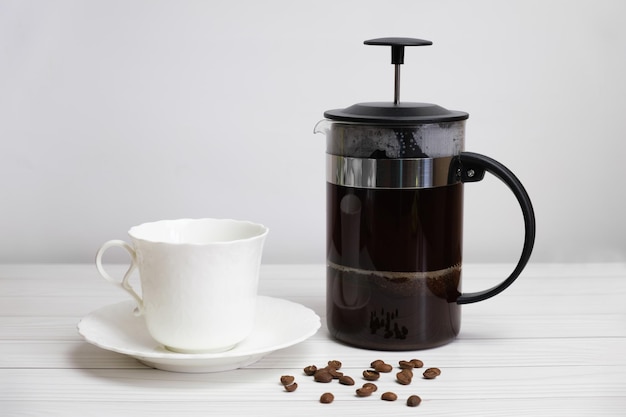 Frenchpressed ground coffee and a white porcelain cup and saucer