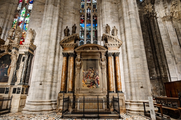 Fresco between the columns under a stained glass window in the duomo milan italy