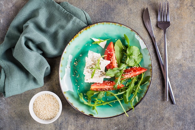 Fresh appetizer of tomatoes feta cheese and arugula on a plate Organic diet Top view