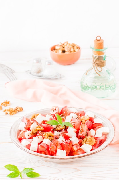 Fresh appetizer of tomatoes, feta cheese, walnuts, flax seeds and sesame seeds in a plate