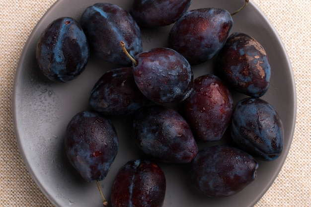 Photo fresh appetizing plums in a gray bowl, summer , copyspace.