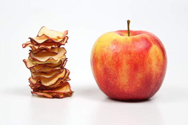 Fresh Apple and a stack of dried Apple slices on white