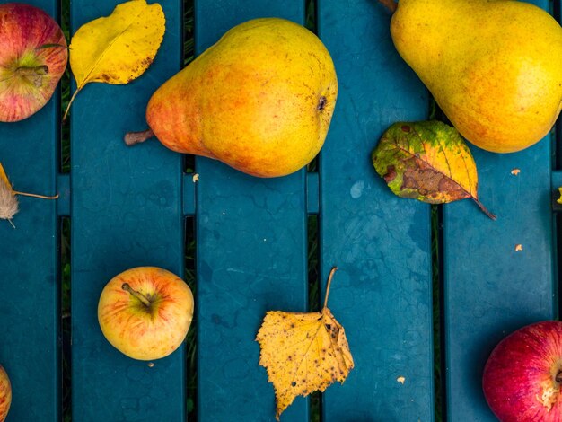 Fresh apples and pears in autumn season yellow and green leaves on garden table