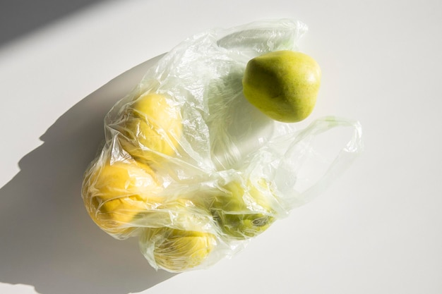 Fresh apples in a plastic bag on a white table Top view flat lay