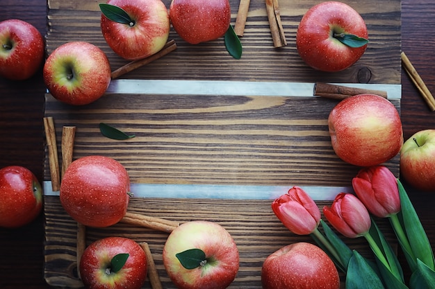 Fresh apples on a wooden board. Harvest of red apples. Fruits and cinnamon on the table.