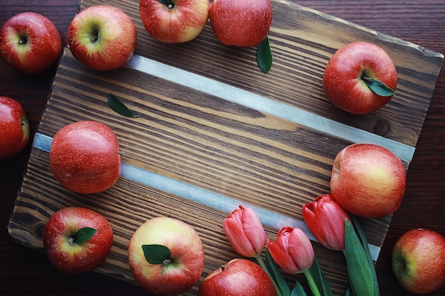 Fresh apples on a wooden board. Harvest of red apples. Fruits and cinnamon on the table.