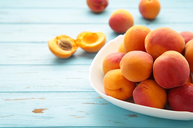 Fresh apricots in the bowl on blue wooden background