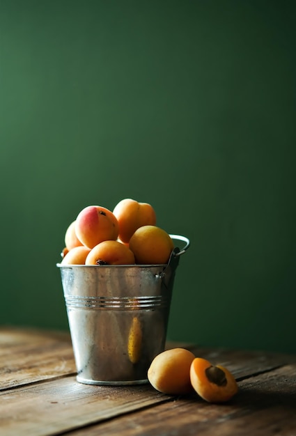 Fresh apricots in a metal bucket Fresh ripe apricots on a wooden table