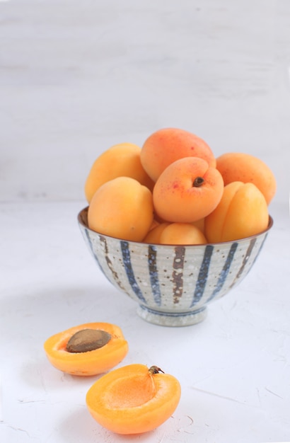 Fresh apricots in white porcelain bowl Summer seasonal fruit  Harvesting Organic fruits Isolated