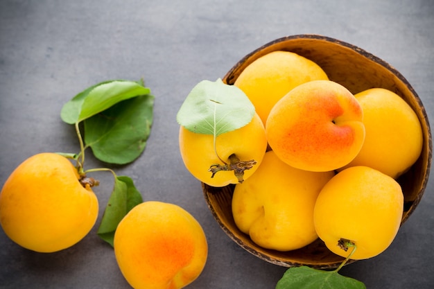 Fresh apricots with leaves on the old wooden table.