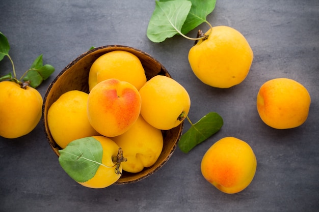 Fresh apricots in wooden bowl on old rustic table.