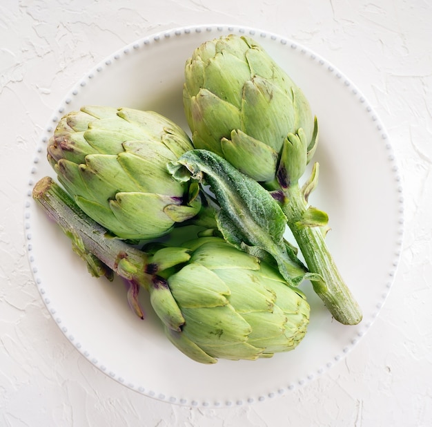 Fresh artichokes on the white plate,  top view