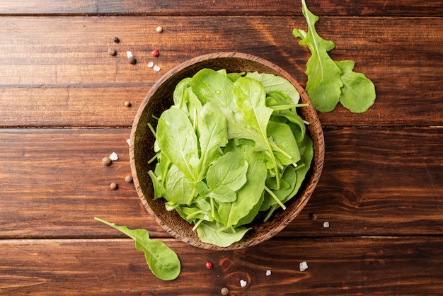 Fresh arugula leaves in brown bowl top view