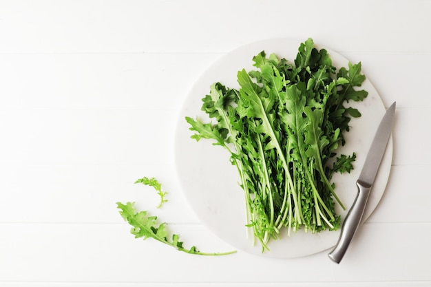 Fresh arugula on marble board with place for text