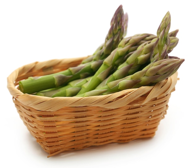 Fresh asparagus in a basket over white background