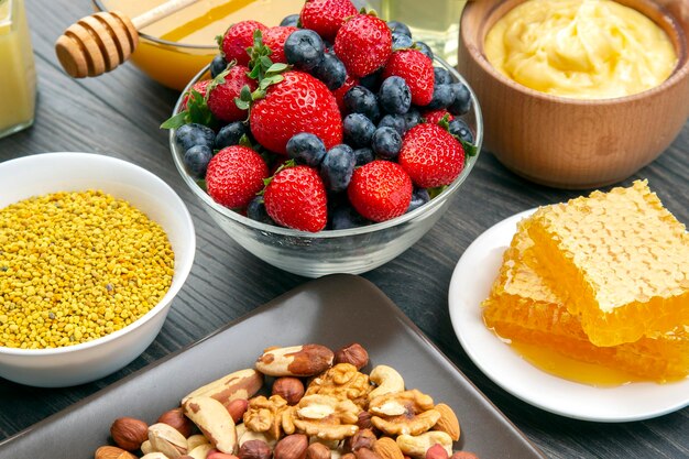 Fresh assorted honey, nuts, strawberries and blueberries on a wooden background. healthy organic vitamin food.