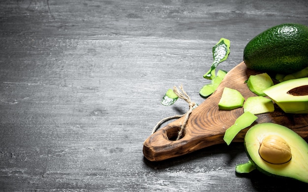 Fresh avocado on the Board. On a black wooden background.