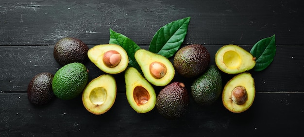 Fresh avocado with leaves on a black background Top view Free space for your text