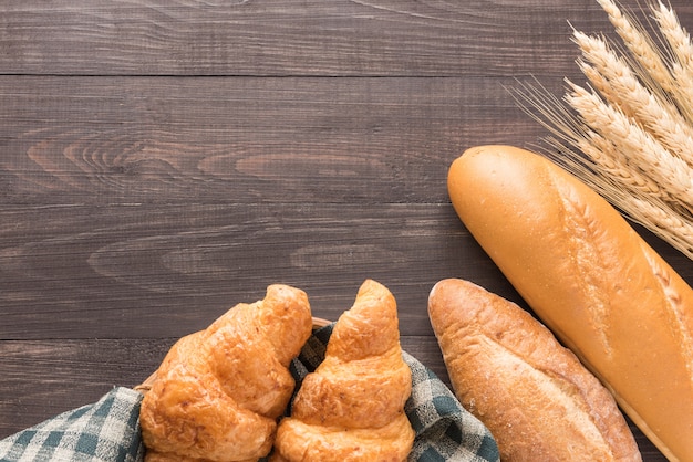 Fresh baked bread and wheat on wooden background