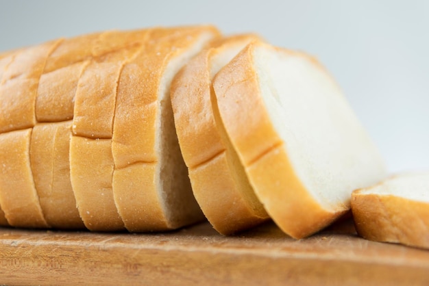 Fresh baked bread on wooden cutting board Bun slice on isolated white background