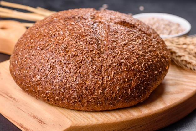 Fresh baked brown bread with ears and grains of wheat