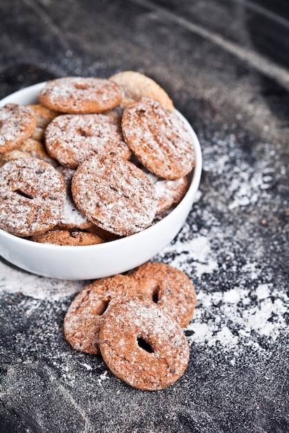 Fresh baked chocolate chip and oat fresh cookies with sugar powder heap in white bowl 