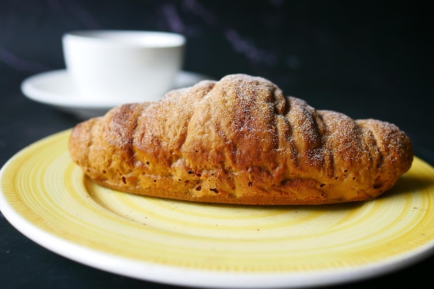 Fresh baked croissant on plate and cup of tea