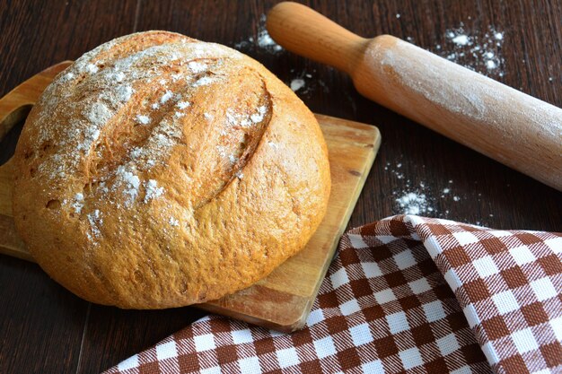 fresh baked loaf of bread on dark wooden background with plunger