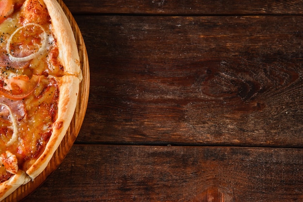 Fresh baked pizza served on rustic wooden table with free space for text. Italian national fast food background, flat lay