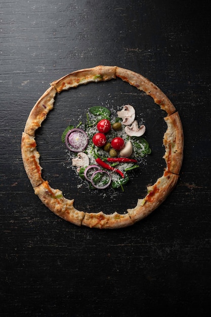 Fresh baked pizza with ingredients on a dark stone table