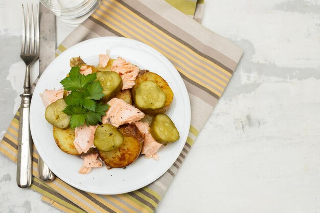 Fresh baked salmon with fried potato and cucumber on plate