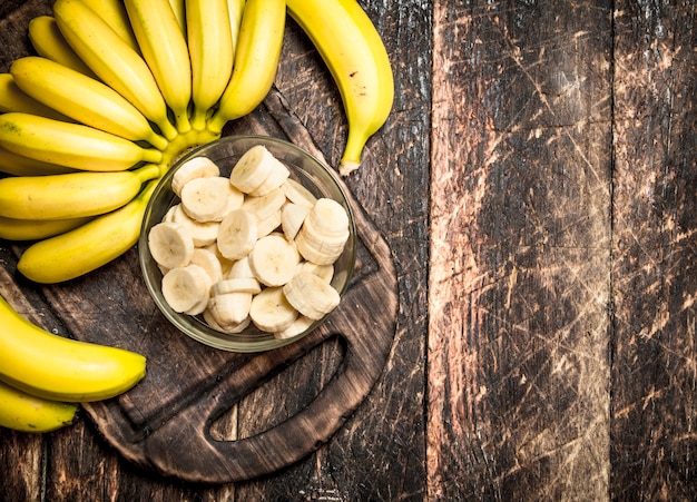 Fresh bananas with chopped pieces in a bowl. On a wooden table.