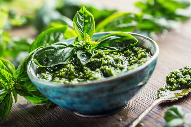 Fresh basil leaves pesto on wooden table.