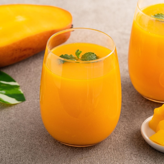 Fresh beautiful delicious mango juice Close up design concept of smoothie cold drink in glass cup with glass straw on gray table background