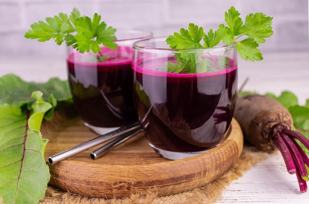 Fresh beetroot juice in glasses with a sprig of parsley.