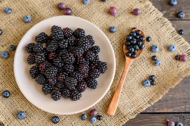 Fresh berries of blueberry, blackberry and gooseberry on a plate. 