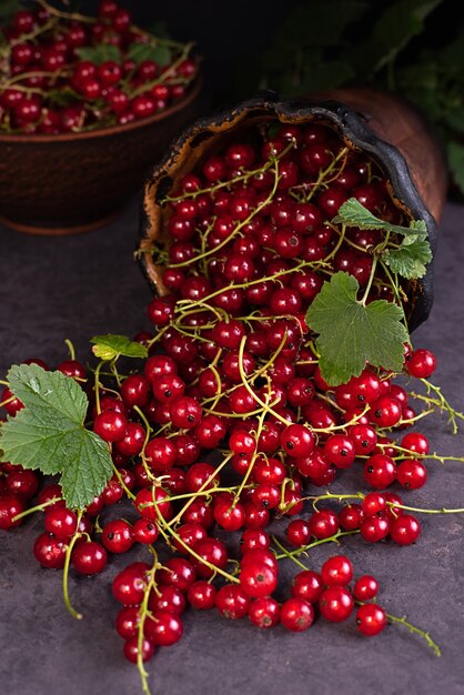 Fresh berries of red currant scattered over a dark background, summer ripe berries, close up.