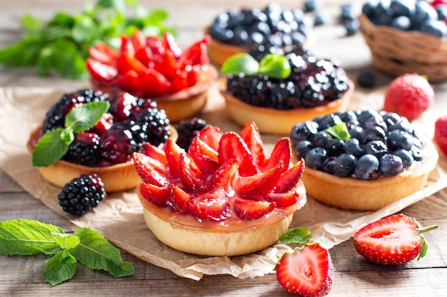 Fresh berries and ricotta cheese in tartletes. Summer dessert, healthy morning breakfast or snack, open sandwiches with strawberry, blueberries, blackberries.