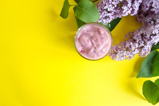 Fresh berry smoothie on a yellow background A branch of lilac and berries smoothie Copy space