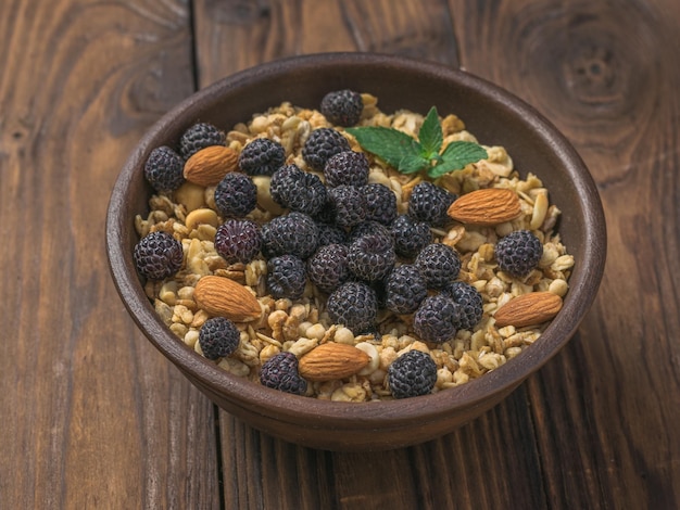 Fresh black raspberries almonds and granola in a clay bowl