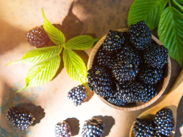 Fresh blackberries in a wooden bowl and spoon on an old table