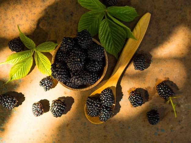 Fresh blackberries in a wooden bowl and spoon on an old table